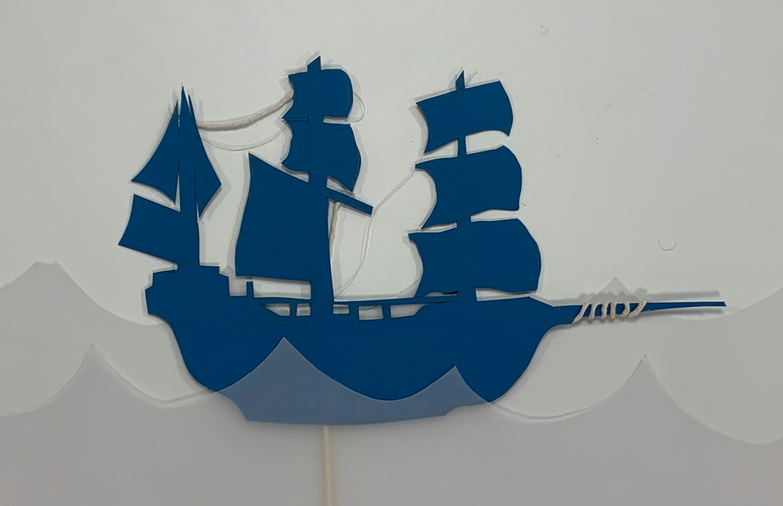 photo of boat cut out from blue card in tracing paper waves